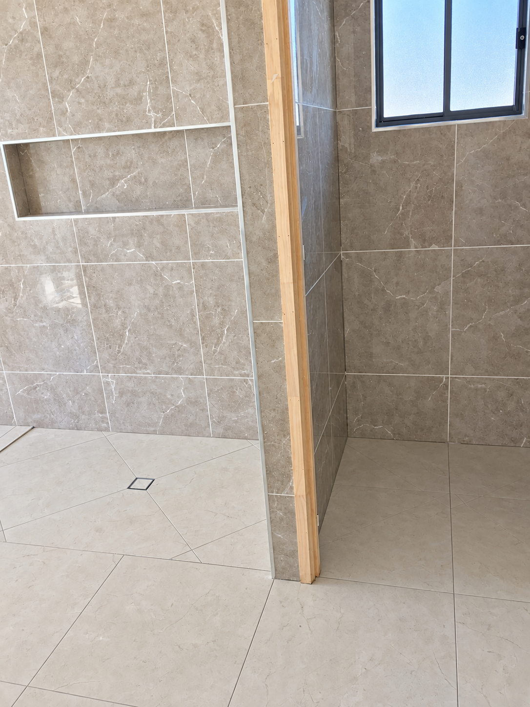 Wide view of tiled bathroom and adjoining wet area