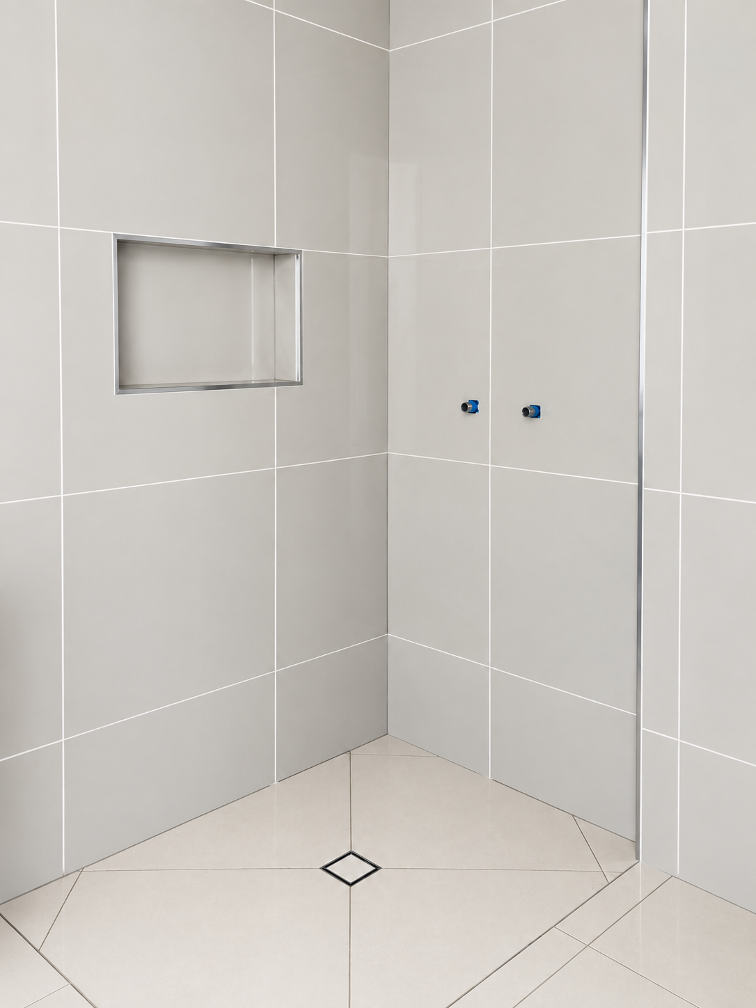 Large-format grey tiled shower with wall niche and tiled falls